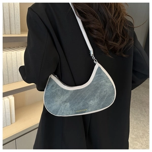 Detail view of denim texture underarm bag with white leather straps and golden logo