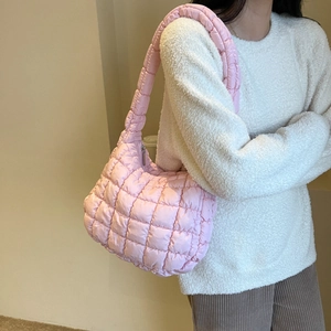 Close-up of pink quilted puffer shoulder bag in nylon material on a model