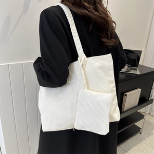 White corduroy tote bag with fashion label and small pouch, shown on shoulder