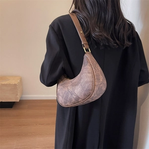 Détail du sac demi-lune marron vintage avec texture nervurée et boucles dorées