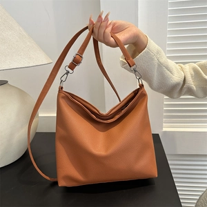 Close-up of adjustable leather shoulder strap and metal zipper on brown crossbody bag