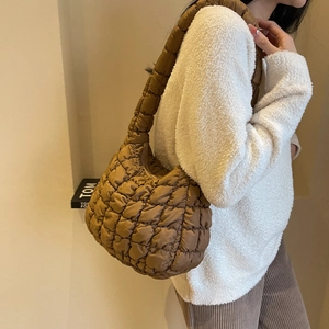 Close-up of brown quilted puffer shoulder bag with soft padded texture on model