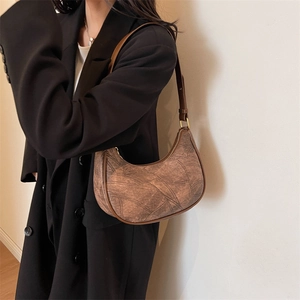 Gros plan d'un sac hobo rétro marron foncé avec texture marbrée porté par un mannequin