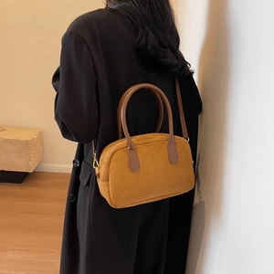 Detailed view of a vintage brown velvet pillow bag featuring sleek handles and a slim strap