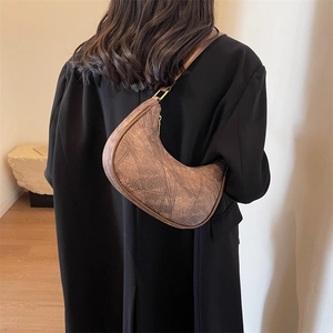 Vue détaillée d'un sac hobo marron vintage en PU avec boucle en cuivre antique sur un manteau