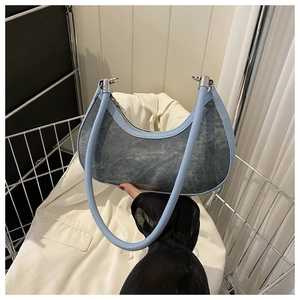 Detailed close-up of a vintage denim hobo bag with leather trim inside a metal cart