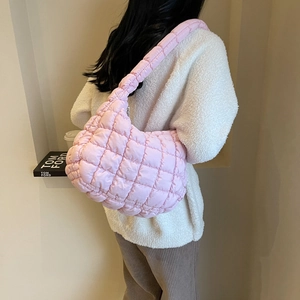Detailed view of light pink quilted shoulder bag with puffy cloud-like design on model