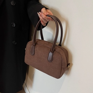 Detail of a brown suede-like pillow bag with leather handles and metallic side buckles