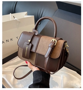 Detail view of contrast color crossbody bag with handle and fashion brand tag