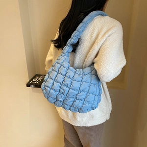 Styling view of a blue quilted hobo bag featuring a fluffy cloud-like texture and zipper