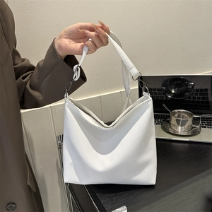 Detail of white lychee pattern PU leather bag with adjustable strap in office setting