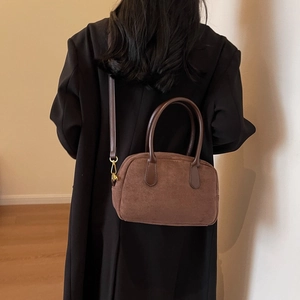 Detail view of brown matte PU leather shoulder bag worn by model in a minimalist home setting