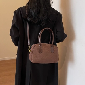 Detailed view of brown suede crossbody bag with leather straps and gold metal hardware