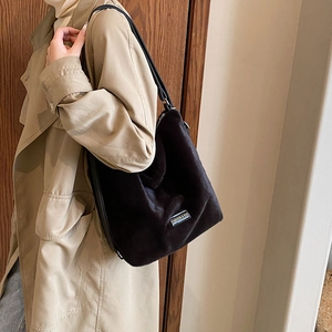 Détail d'un sac cabas en fausse fourrure noire avec étiquette en métal et bandoulière