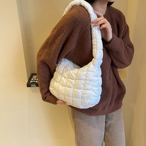 Detail view of the white quilted puffy bag texture and comfortable wide shoulder strap