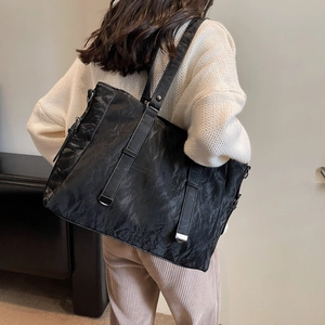 Detail of black tote bag with marble texture, silver hardware and slim shoulder strap