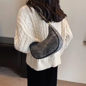 Vue détaillée d'un sac hobo en demi-lune gris vintage porté avec un pull en maille douce