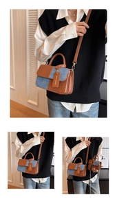 Detailed close-up of color-block leather and denim handbag with gold hardware and logo tag