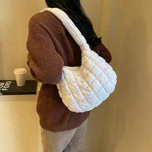 Back view of a model wearing a white quilted crescent shoulder bag with a puffy texture