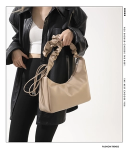 Vue détaillée de la poignée plissée beige et de la surface en cuir PU de ce sac à main