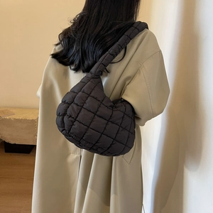 Detail of black quilted puffer bag showing square padding texture on a nylon shoulder bag