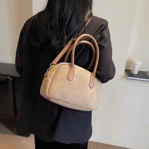 Brown faux suede Boston bag with leather straps worn by model in minimalist studio