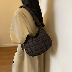 Detail of dark brown quilted puffer tote bag with glossy nylon texture and silver zipper