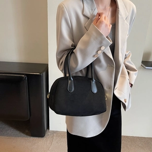Detail of a black suede-textured Boston bag showing dual leather handles and D-ring