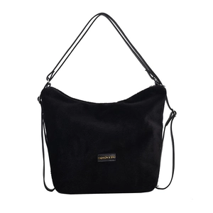 Sac à épaule en peluche noire pour femme avec étiquette en cuir sur fond blanc épuré