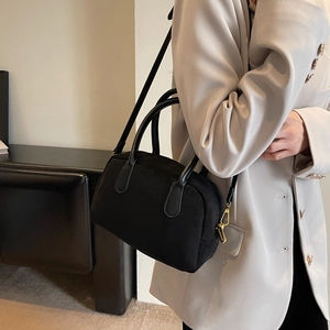 Detail of black suede crossbody bag with gold hardware worn with beige blazer
