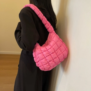 Detail of pink quilted puffer hobo bag with bubble texture on a model wearing black