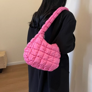 Detail of pink quilted puff shoulder bag fabric texture on person with black coat