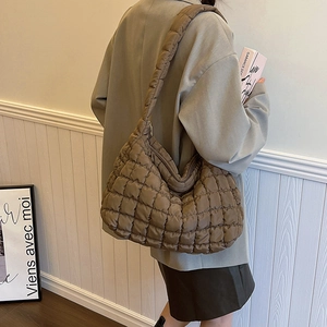 Detail shot of a dark brown quilted cloud shoulder bag with textured square pattern