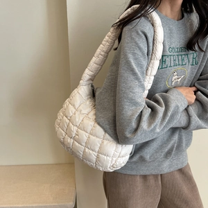 Close-up of cream white quilted puffer shoulder bag with soft satin texture