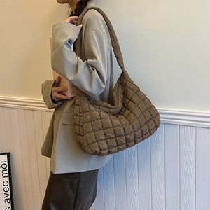 Close-up of quilted coffee brown underarm bag with soft puffer texture and zip closure