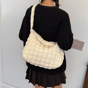Detailed back view of a white quilted puffer shoulder bag styled on a black sweatshirt
