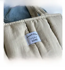 Close-up of beige quilted puffer tote bag detail with brand label on fabric