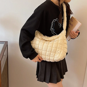 Detailed shot of cream quilted nylon shoulder bag with soft padded texture and wide strap