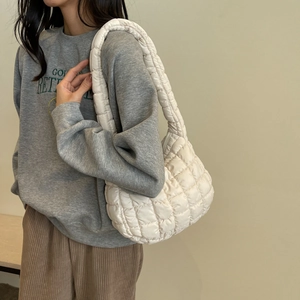 Close-up of a quilted cream shoulder bag with soft padded fabric and crescent moon design