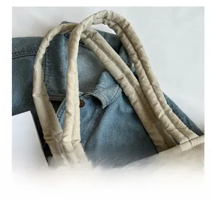 Detailed close-up of quilted beige tote bag with soft padded handles on denim
