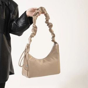 Sac hobo beige avec bandoulière plissée style nuage et détails de pompons latéraux