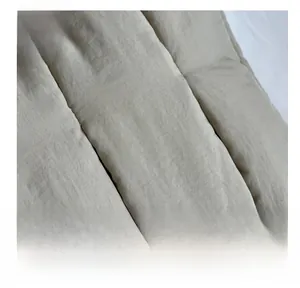 Detail view of the soft quilted fabric texture and brand label on a beige tote bag