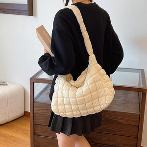Detail of off-white quilted puffer hobo bag with a soft padded shoulder strap on model