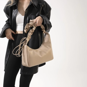Sac sous le bras beige avec poignée plissée en similicuir porté par un mannequin