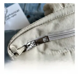 Close-up of smooth metal zipper on beige quilted padded puffer tote bag detail