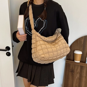 Quilted crossbody bag shown on a model in a cozy indoor setting with books