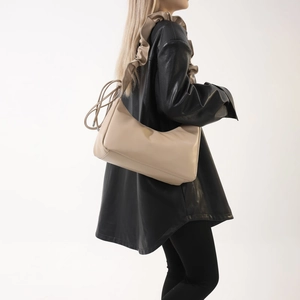 Vue détaillée du sac beige avec bandoulière à volants et pompons de serrage