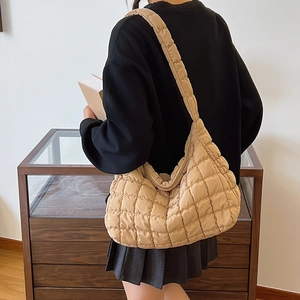 Detailed close-up of beige quilted puffer shoulder bag with soft textured fabric