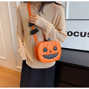 Detail of pumpkin crossbody bag with orange leather, bat strap and gold hardware
