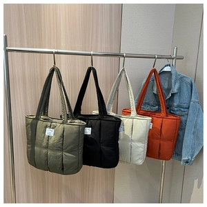Detailed macro view of quilted down tote bags in olive, black, beige, and orange colors